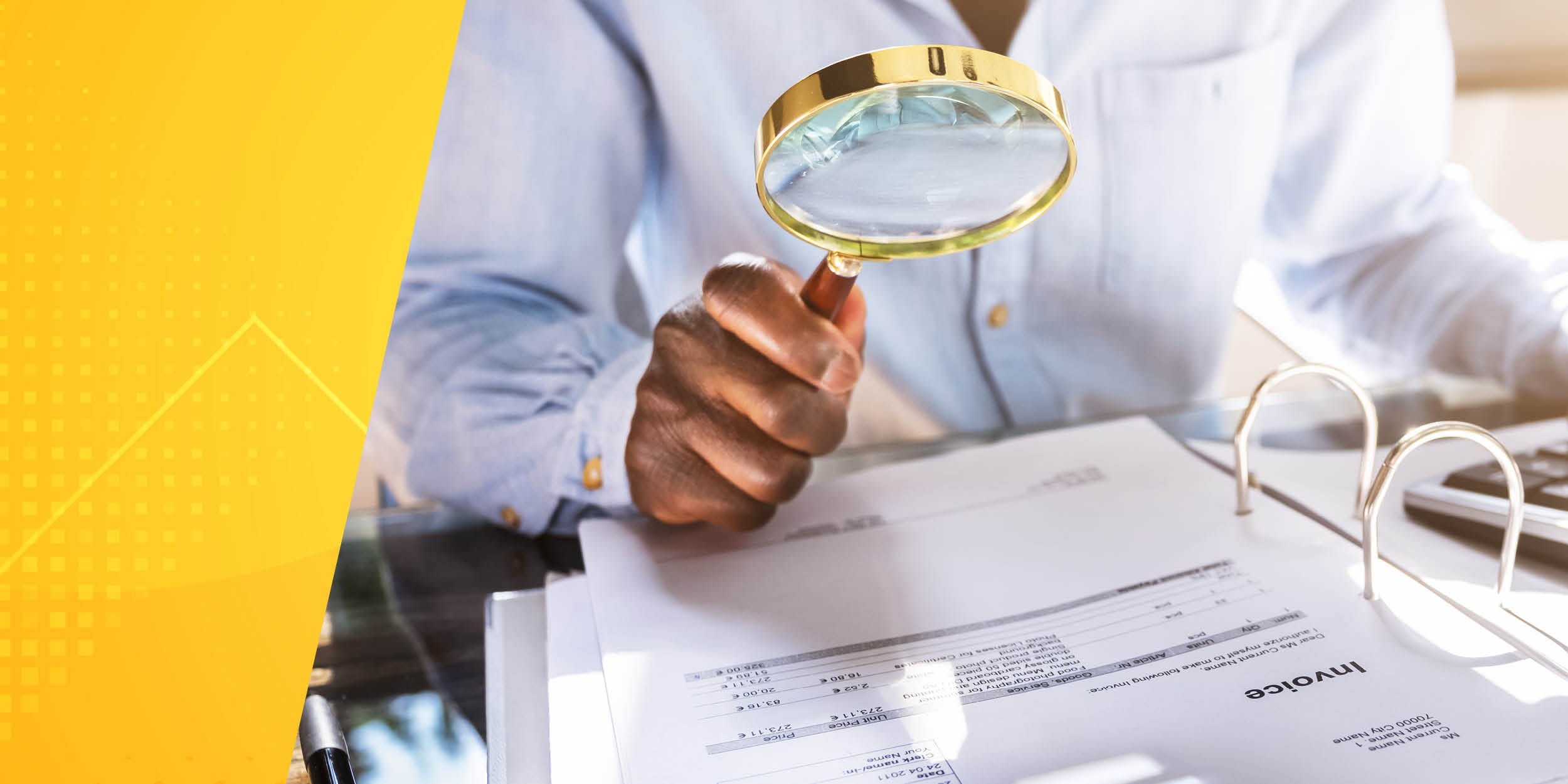 hand holding magnifying glass over paperwork